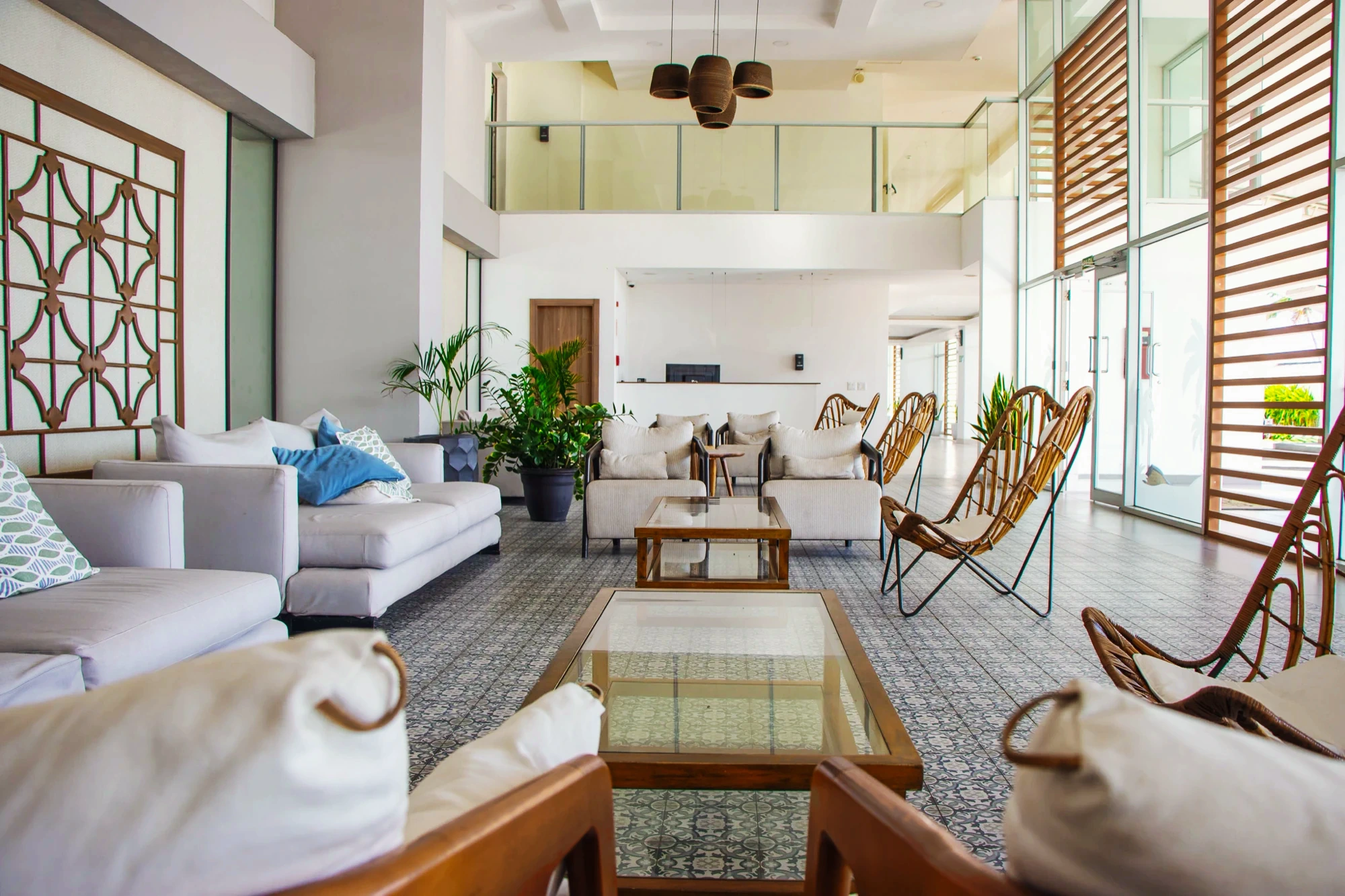 White sofas and butterfly chairs fill Royal Palm's double-height lounge over patterned tile